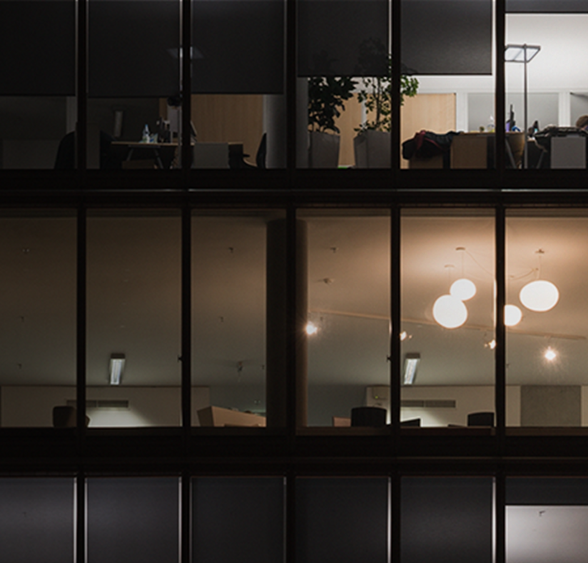 Een foto van drie vooral onverlichte verdiepingen in een kantoorgebouw met meerdere verdiepingen bij nacht.